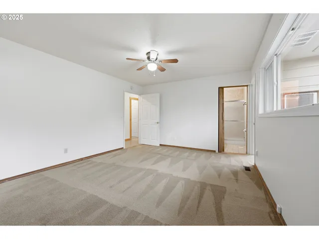 a view of an empty room with chandelier fan