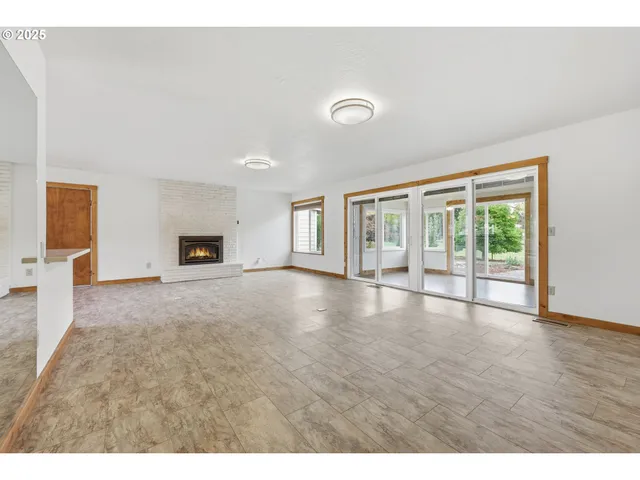a view of empty room with wooden floor and kitchen view