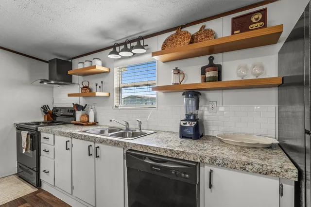 a kitchen with stainless steel appliances granite countertop a sink a stove and cabinets