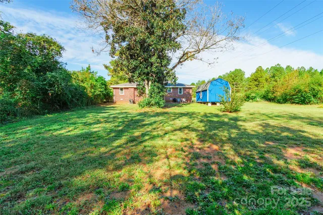 a backyard of a house with plants and large trees
