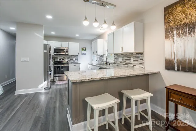 a kitchen with stainless steel appliances kitchen island granite countertop a table chairs sink and cabinets