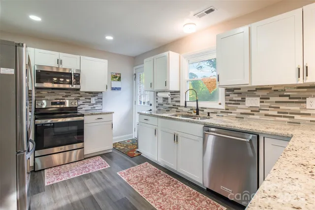 a kitchen with stainless steel appliances granite countertop a stove a sink and a refrigerator