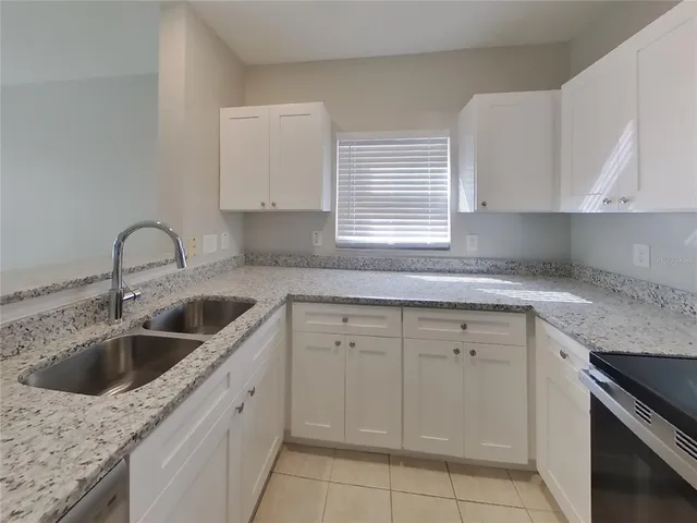 a kitchen with white cabinets appliances a sink and a window