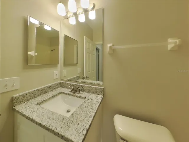 a bathroom with a granite countertop sink and a mirror