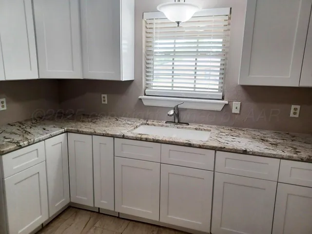 a kitchen with granite countertop white cabinets and sink
