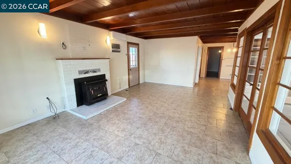 a view of an empty room with wooden floor and a fireplace
