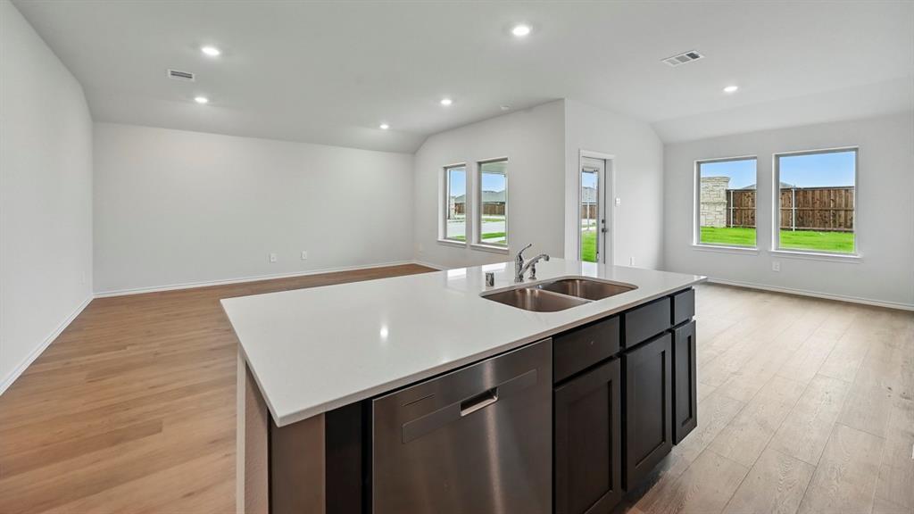 1908 Freeman Street Tyler, TX 75704 - Photo 4 of 30 Kitchen island featuring a double basin stainless steel sink, stainless steel dishwasher, and dark cabinetry