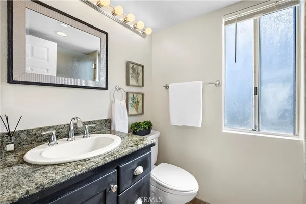 a bathroom with a granite countertop sink a mirror and a toilet