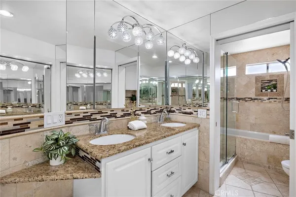 a bathroom with a granite countertop sink a mirror and a shower