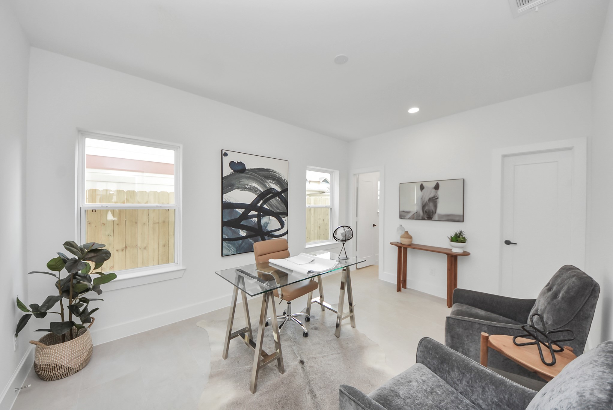 927 Fisher Street, Unit B Houston, TX 77018 - Photo 6 of 47 Step into this bright, modern home office, where a glass desk and comfortable seating are complemented by stylish artwork and minimalistic decor. Large windows fill the space with natural light, while neutral walls create an inviting and functional environment perfect for focused work or study.