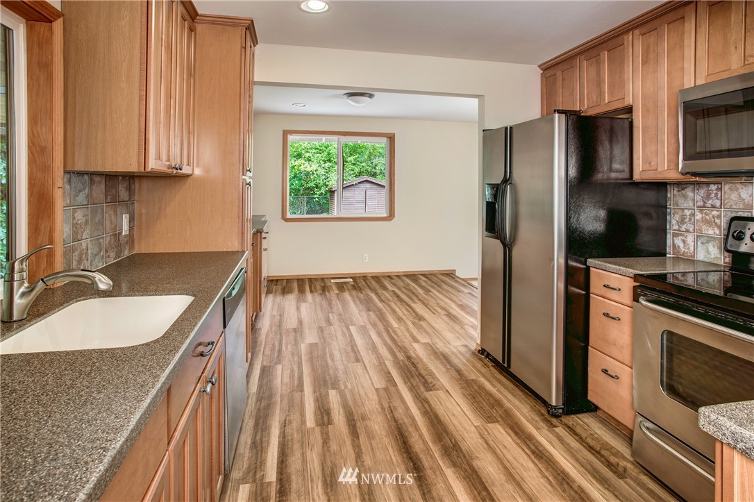 14437 157th Place Southeast Renton, WA 98059 - Photo 5 of 18 a kitchen with kitchen island granite countertop a sink stove and refrigerator