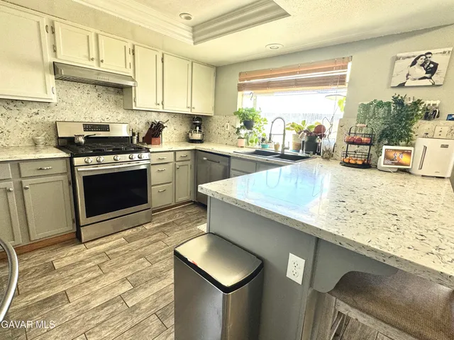 a kitchen with stainless steel appliances granite countertop a sink stove and cabinets