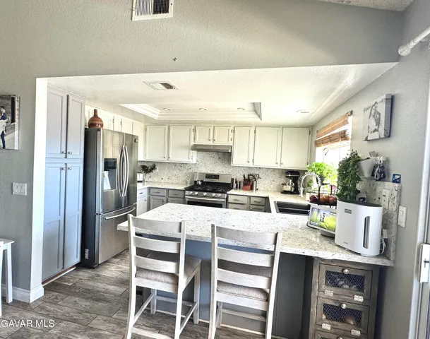 a kitchen with stainless steel appliances kitchen island granite countertop a refrigerator and a stove top oven