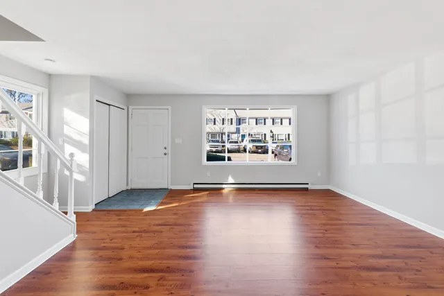 a view of an empty room with window and wooden floor