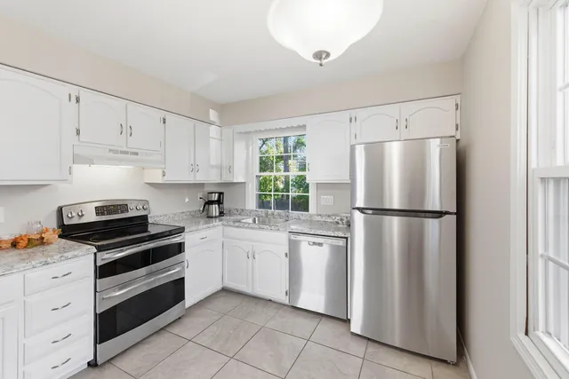 a kitchen with white cabinets and white appliances