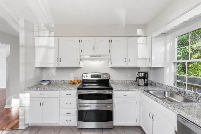 a kitchen with cabinets appliances a sink and a window