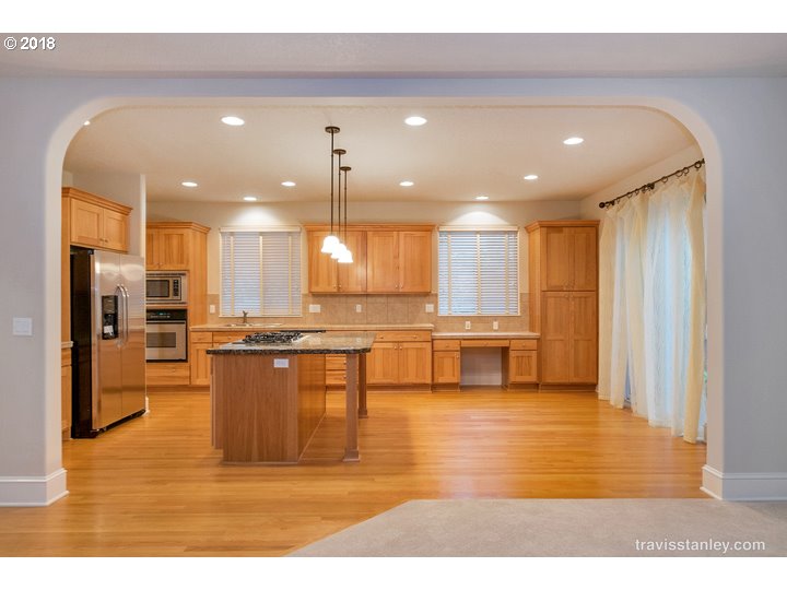 4636 Northwest Corazon Terrace Portland, OR 97229 - Photo 5 of 18 a kitchen with stainless steel appliances kitchen island granite countertop a refrigerator a stove and a sink