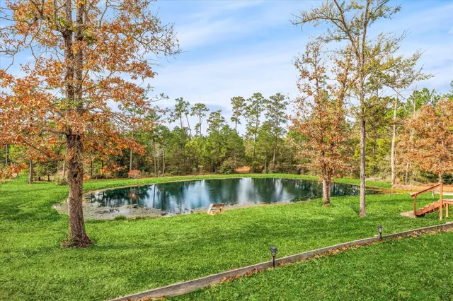 a view of a lake with a yard and large trees