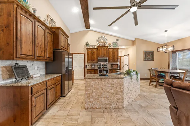 a large kitchen with stainless steel appliances kitchen island granite countertop a refrigerator a stove top oven a sink with a dining table and chairs
