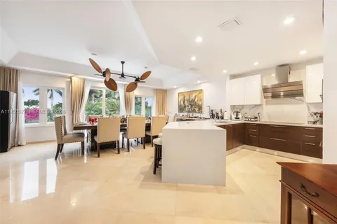 a living room with stainless steel appliances kitchen island granite countertop a dining table chairs and a large window