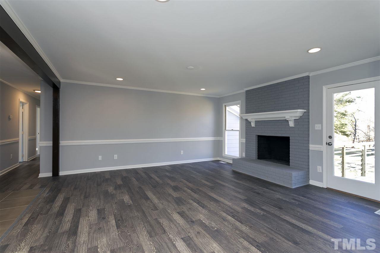 2016 Howson Road Raleigh, NC 27603 - Photo 13 of 25 an empty room with wooden floor fireplace and windows
