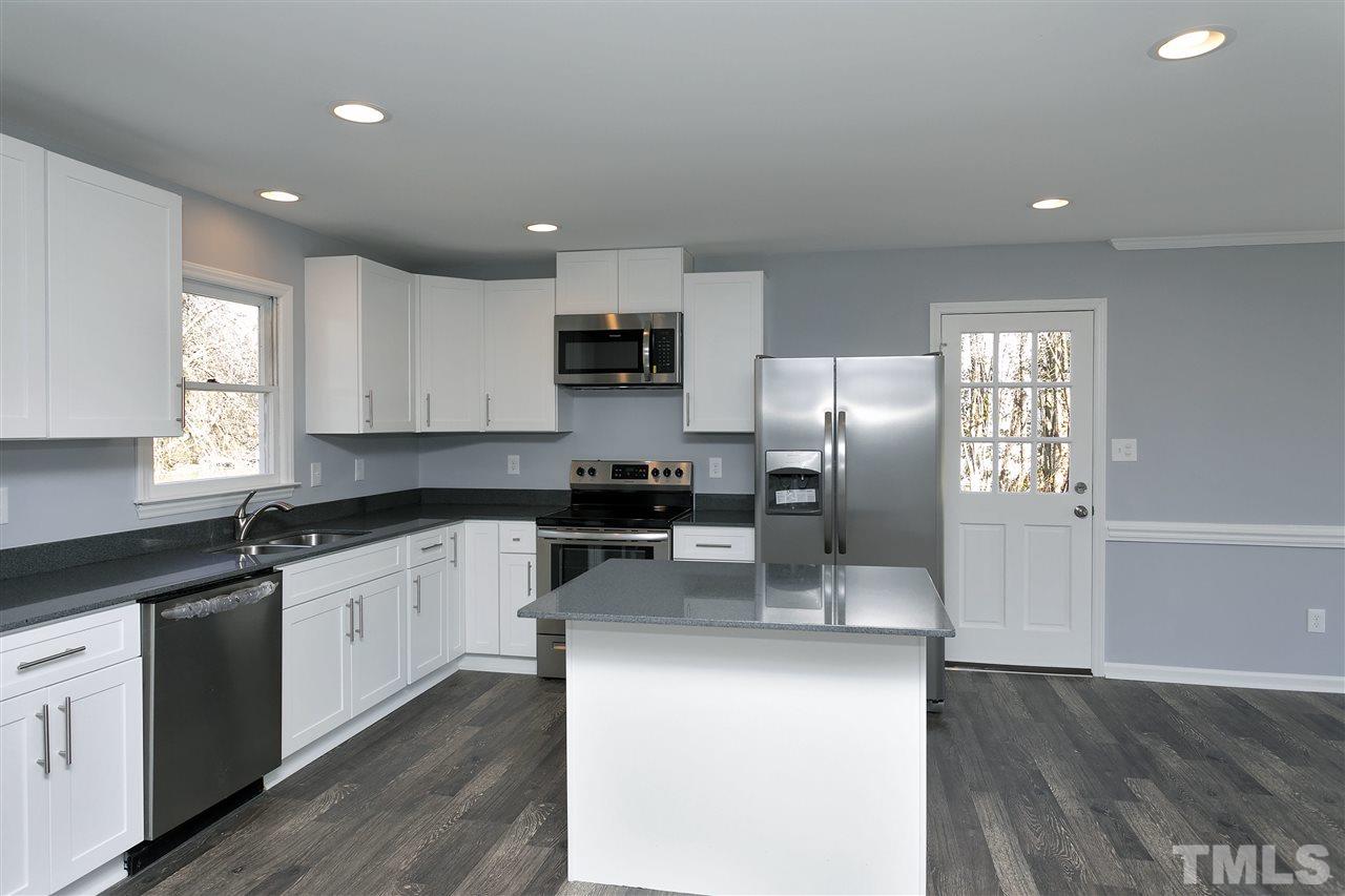 2016 Howson Road Raleigh, NC 27603 - Photo 8 of 25 a kitchen with granite countertop a refrigerator a sink a stove a microwave and wooden cabinets