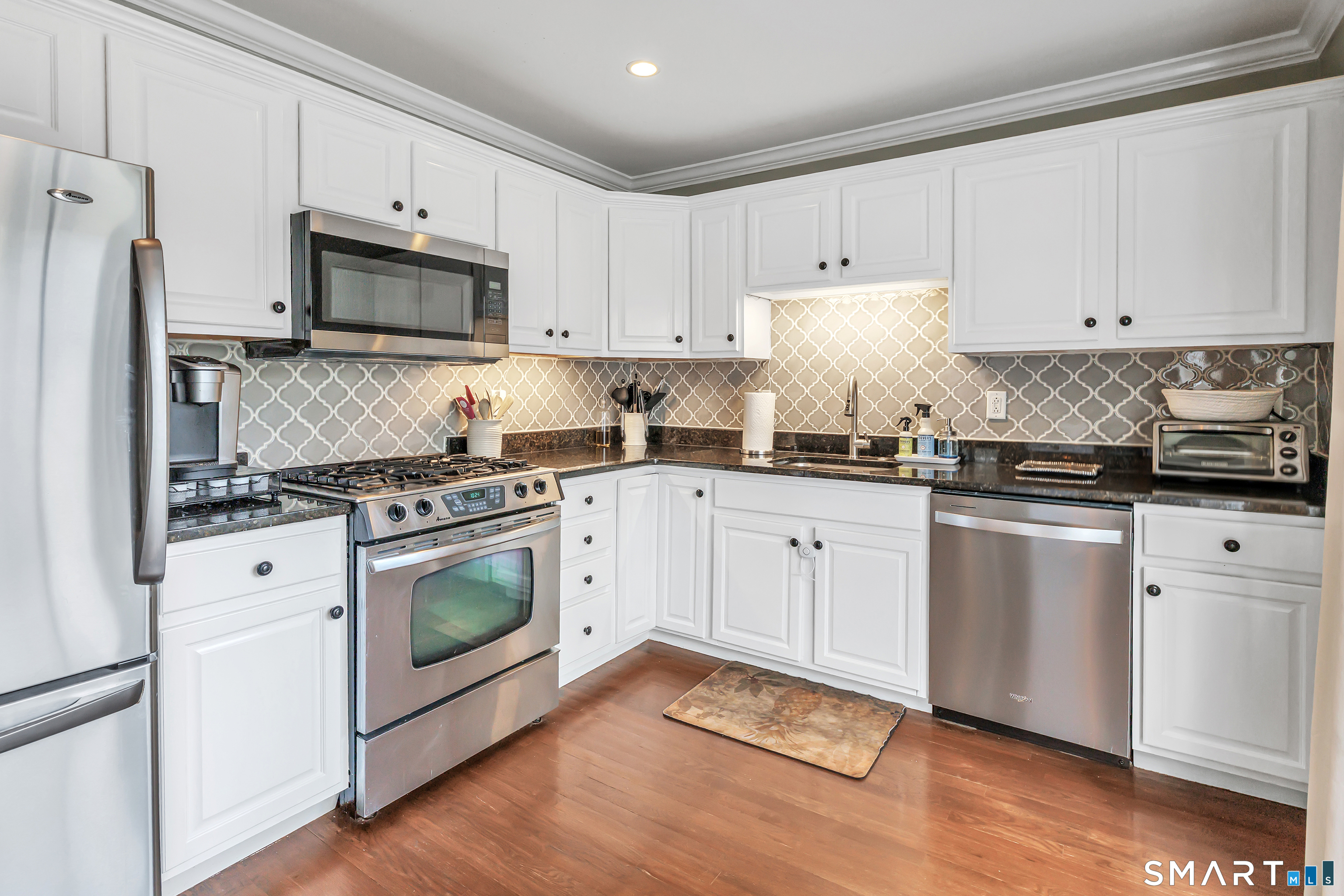 39 Maple Tree Avenue, Unit 15 Stamford, CT 06906 - Photo 3 of 32 a kitchen with granite countertop white cabinets sink and stainless steel appliances