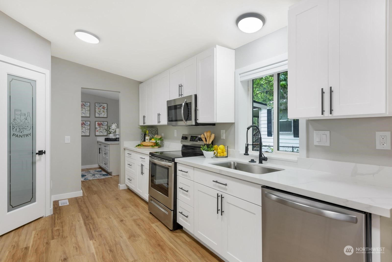 20500 32nd Drive Southeast Bothell, WA 98012 - Photo 4 of 28 a kitchen with a sink dishwasher stove and white cabinets with wooden floor