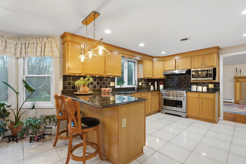 22 Magnolia Road Sharon, MA 02067 - Photo 5 of 42 a kitchen with stainless steel appliances kitchen island granite countertop a table chairs and a refrigerator