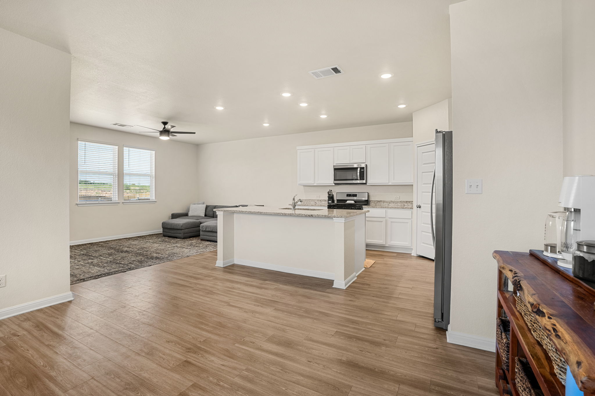 148 Hidalgo Lane Elgin, TX 78621 - Photo 12 of 38 An open concept living area boasts a central kitchen island and durable plank flooring.