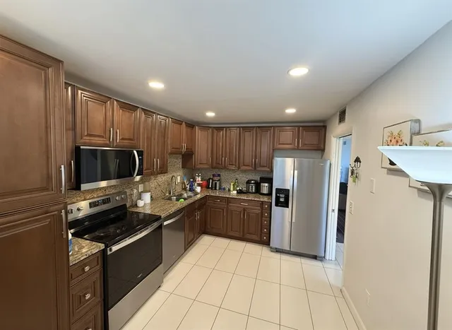 a kitchen with stainless steel appliances granite countertop a refrigerator and a stove top oven