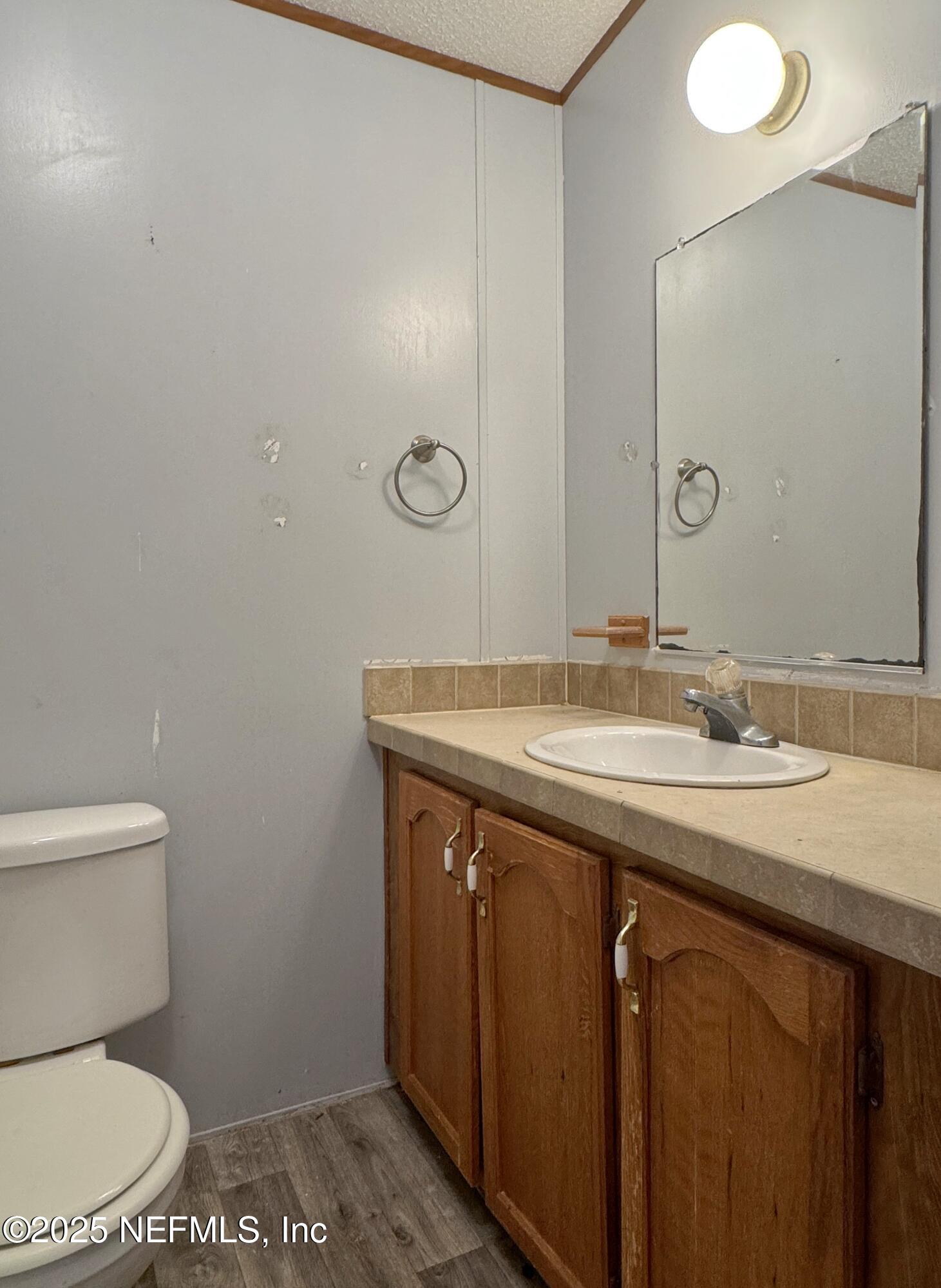 132 Long Road Interlachen, FL 32148 - Photo 18 of 21 a bathroom with a granite countertop sink a toilet and a mirror