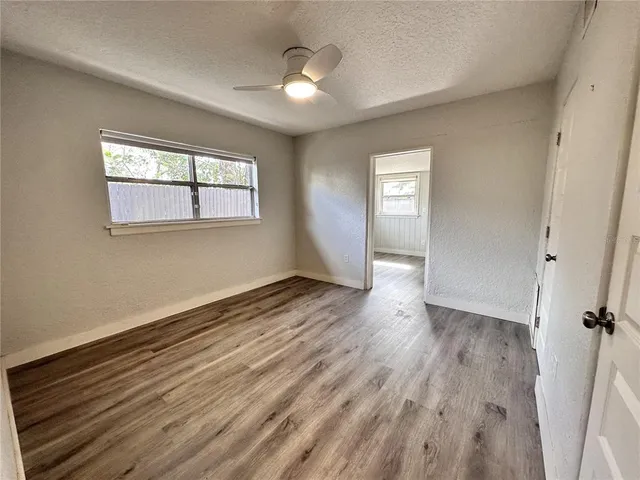 a view of an empty room with wooden floor and a window