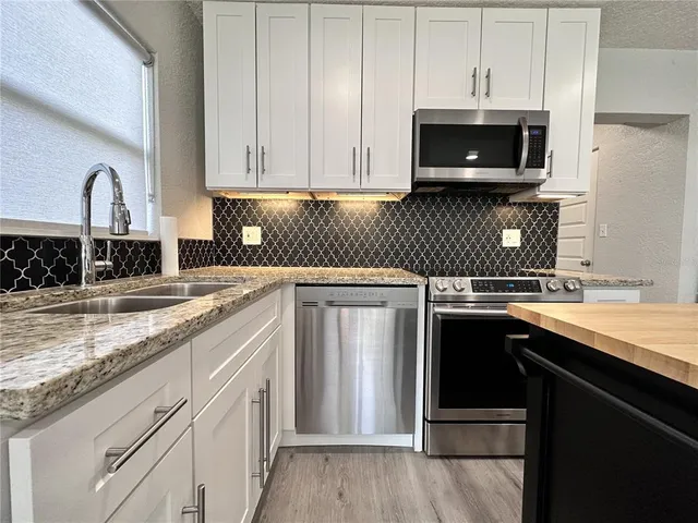 a kitchen with stainless steel appliances granite countertop a sink stove and microwave