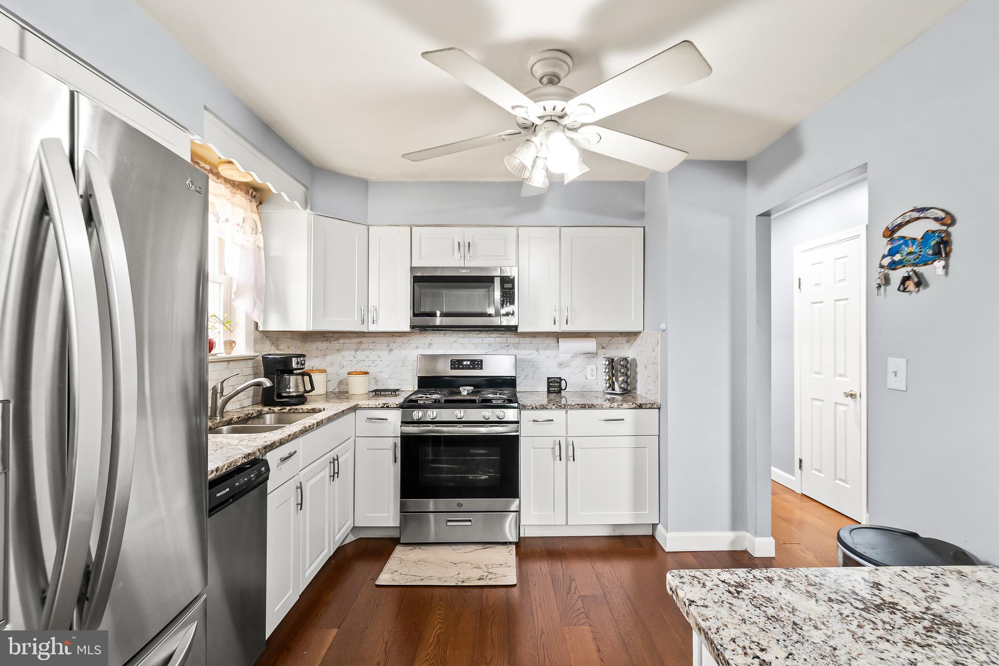11411 Hermitt Street Clinton, MD 20735 - Photo 12 of 40 a kitchen with stainless steel appliances a stove a sink dishwasher a refrigerator white cabinets and wooden floor