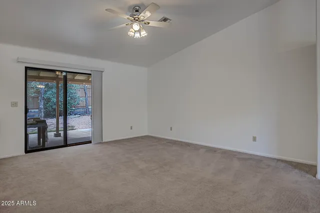 a view of an empty room with chandelier fan