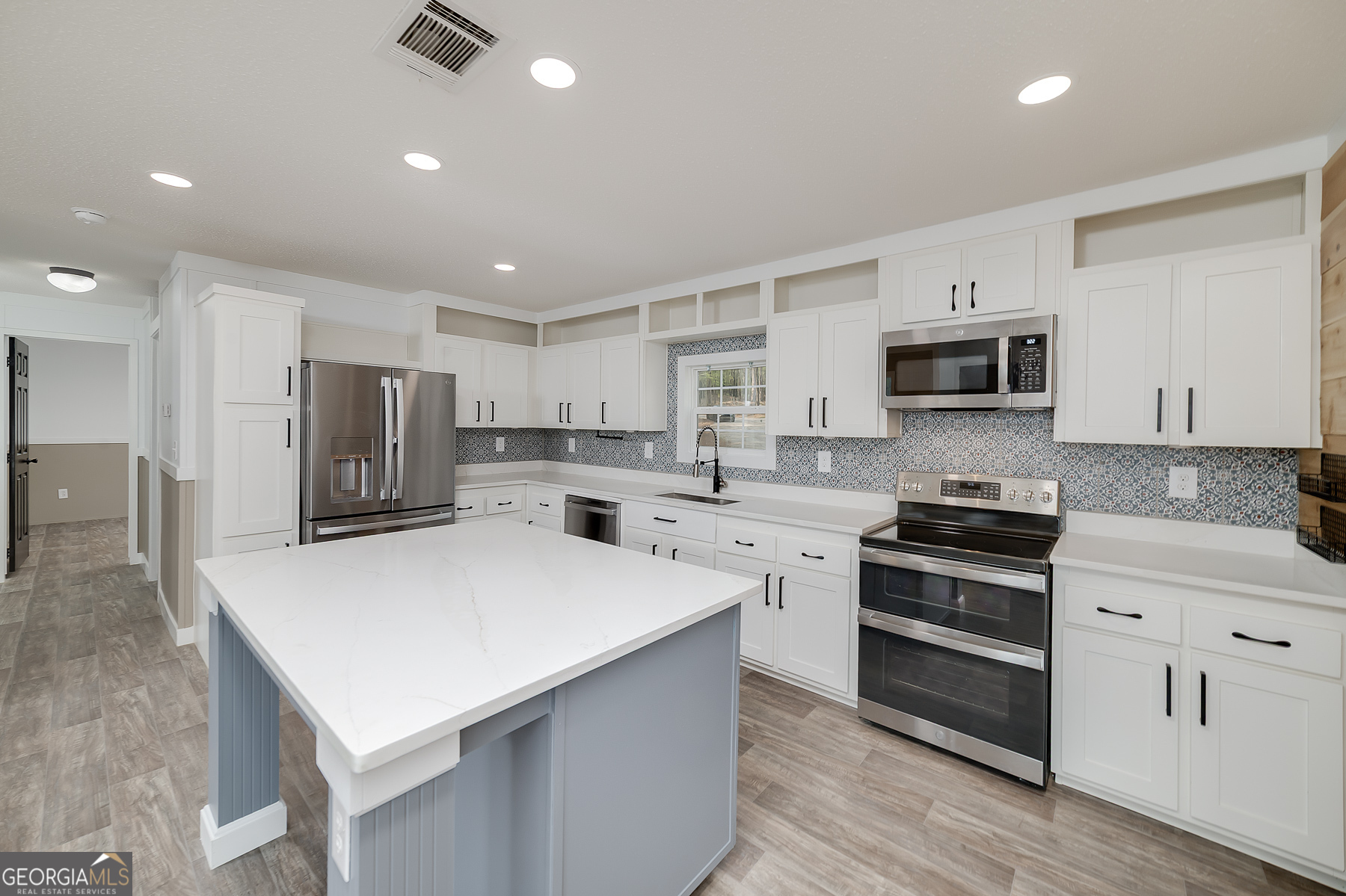 595 Barnetts Bridge Road Jackson, GA 30233 - Photo 20 of 47 a kitchen with stainless steel appliances a stove top oven a sink a refrigerator white cabinets and wooden floor