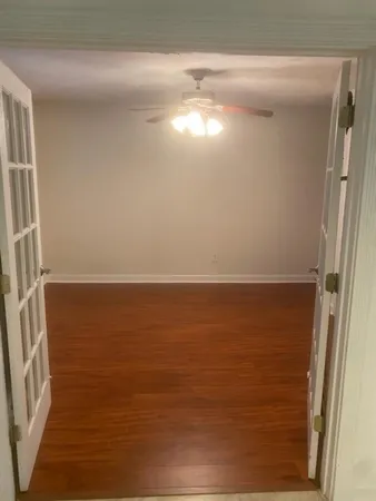 a view of an empty room with wooden floor and a window