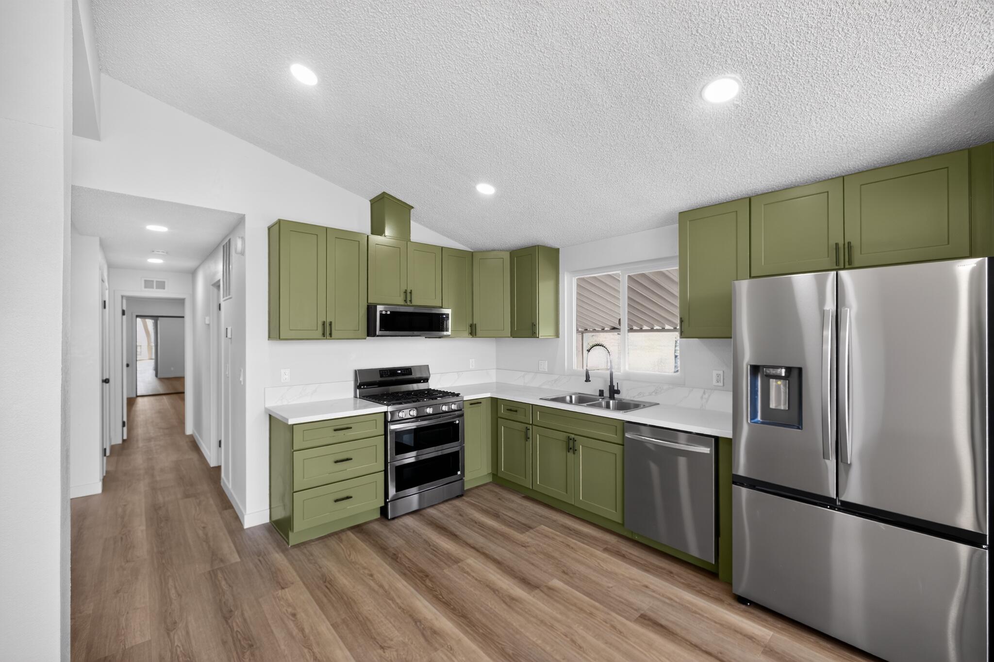 15181 Van Buren Boulevard, Unit 102 Riverside, CA 92504 - Photo 11 of 29 a kitchen with stainless steel appliances granite countertop a refrigerator a sink dishwasher a oven with white cabinets and wooden floor