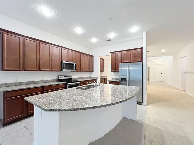 a kitchen with stainless steel appliances granite countertop a sink a stove a refrigerator a center island and cabinets