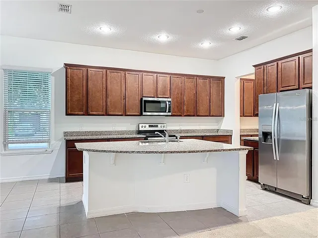 a kitchen with stainless steel appliances granite countertop a stove a sink a microwave and a refrigerator