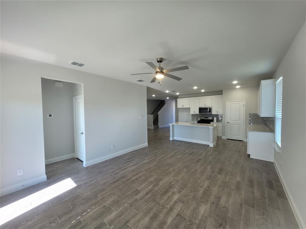 2702 Island Palm Court Forney, TX 75126 - Photo 4 of 15 a view of an empty room with wooden floor and a kitchen