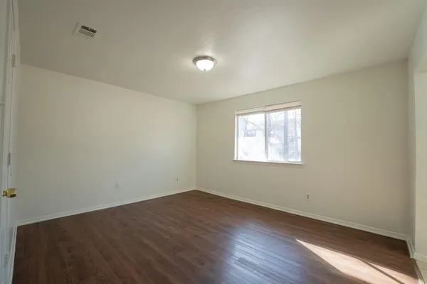 an empty room with wooden floor and windows