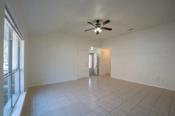 a view of an empty room with chandelier fan and a window