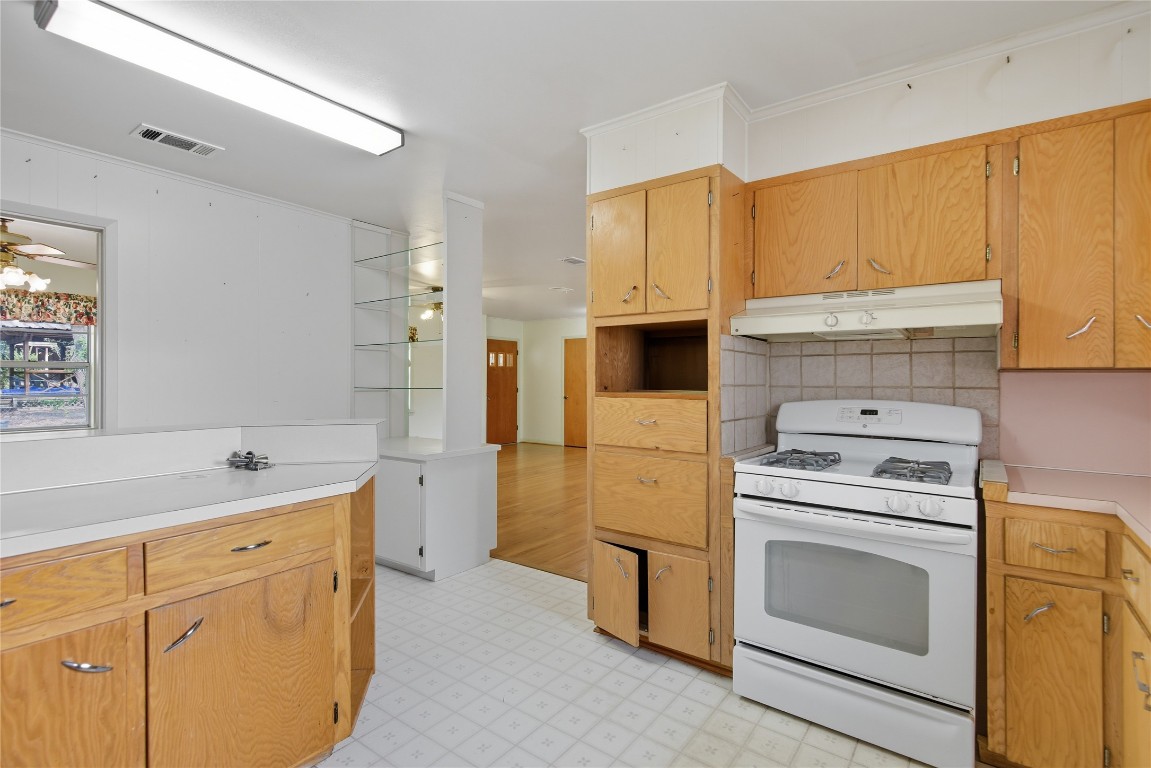 508 Morris Drive Georgetown, TX 78628 - Photo 16 of 40 Kitchen featuring white gas range oven, light countertops, light floors, decorative backsplash, and under cabinet range hood