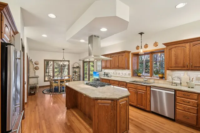 a kitchen with stainless steel appliances granite countertop a sink stove and wooden floor