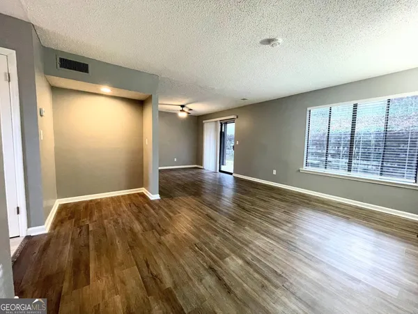 a view of empty room with wooden floor and fan