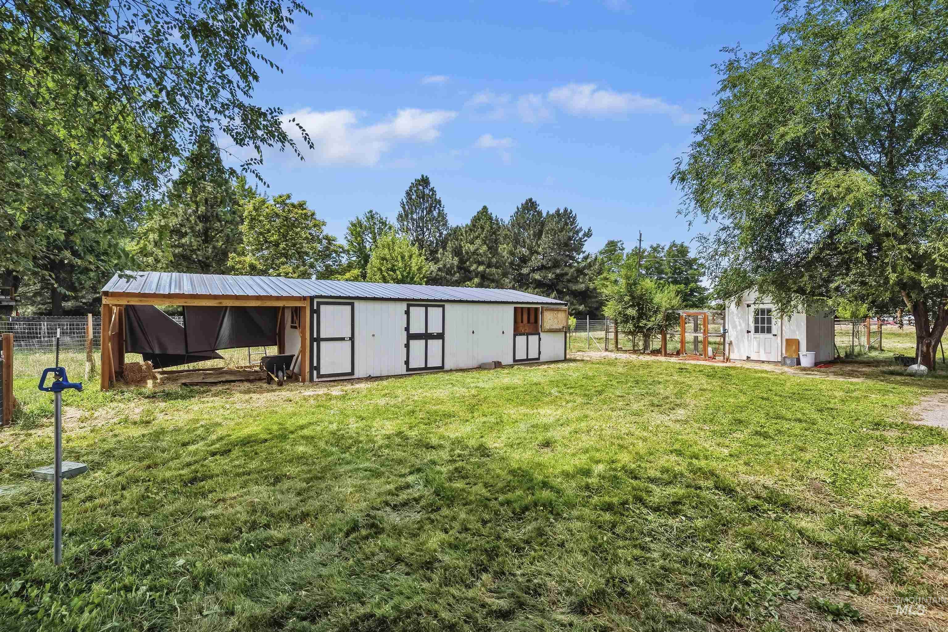 355 East Beacon Light Road Eagle, ID 83616 - Photo 32 of 47 Expansive grassy yard featuring a long white outbuilding with multiple black doors and a metal roof