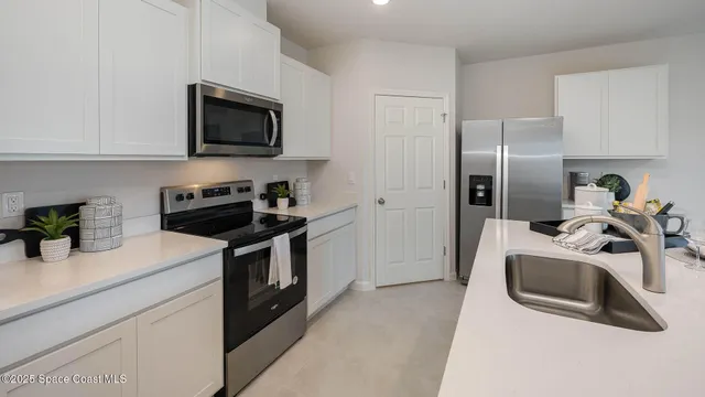 a kitchen with stainless steel appliances granite countertop a sink a microwave a refrigerator a stove and white cabinets