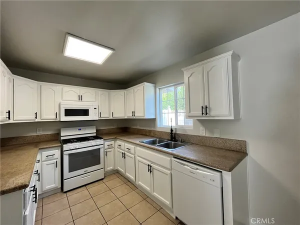 a kitchen with granite countertop a sink stainless steel appliances white cabinets and a window